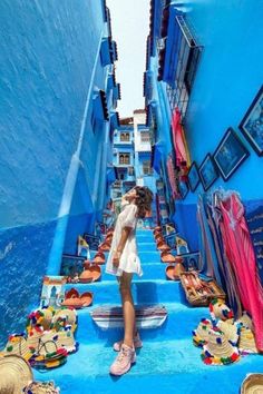 a woman standing in the middle of a narrow alleyway with blue walls and flooring