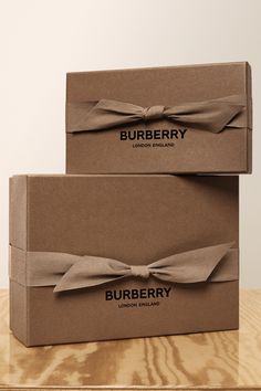 two brown boxes with bows on them sitting on a wooden table next to each other