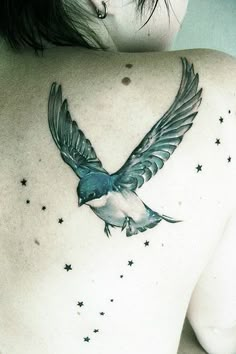 a woman's back with a bird and stars tattoo on her left side shoulder