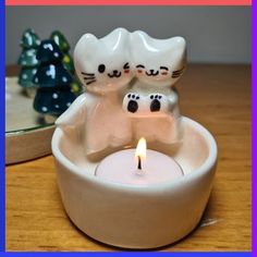 two cats sitting in a bowl with a candle