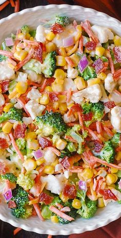 a white bowl filled with corn, broccoli and carrots on top of a table