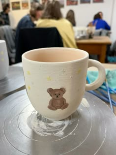 a cup with a teddy bear painted on it sitting on top of a metal table