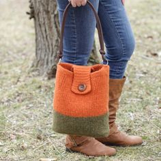 a woman wearing boots and holding a purse in her hand while standing next to a tree