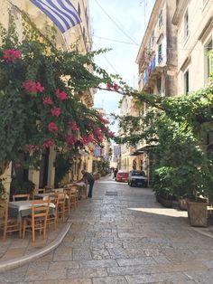 an empty street with tables and chairs lined up on the side walk, next to parked cars