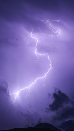 a purple sky with lightning and clouds in the background