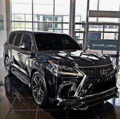 the front end of a black suv in a showroom with glass walls and large windows