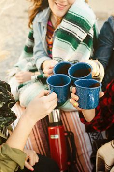 three people sitting on a bench holding cups