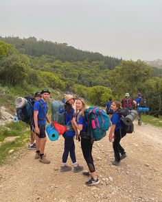 group of people with backpacks walking down a dirt road