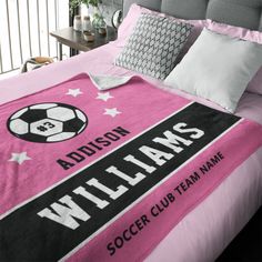 a pink soccer blanket with the name and team name on it sitting on a bed