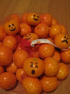 oranges with faces drawn on them sitting in a bowl