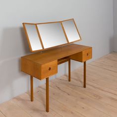 a wooden desk with two mirrors on it's top and one drawer under the mirror