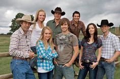 a group of people standing next to each other in front of a fence and grass field