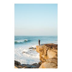 a man standing on top of a cliff next to the ocean