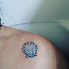 a woman with a tattoo on her shoulder has a seashell in the shape of a starfish