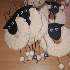 three sheep made out of yarn and balls on a table with decorations around them that look like they have eyes