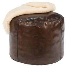 a brown leather ottoman with a white blanket on it's top and the foot rest