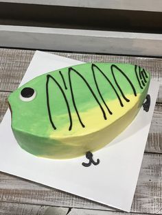 a cake shaped like a fish on top of a piece of paper with black icing