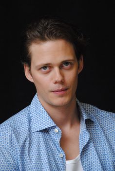 a man in a blue and white shirt looking at the camera with a serious look on his face