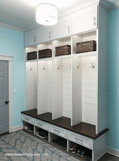 a room with some white cabinets and shoes on the floor in front of a blue wall