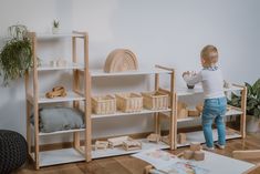 a young child playing with wooden toys in a room filled with plants and other items