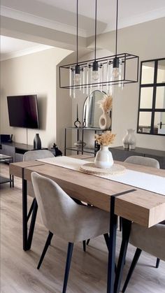 a dining room table with chairs and a vase on top of it in front of a television