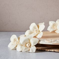 two white flowers sitting on top of a cutting board