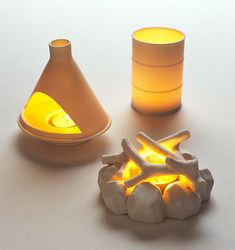 three different shapes and sizes of candles on a table with one lit candle in the middle