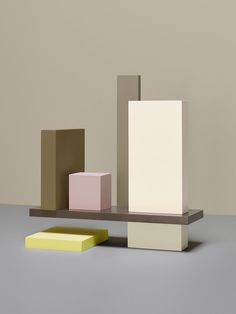 three different colored blocks on a shelf with one yellow block in the middle and one pink block at the bottom