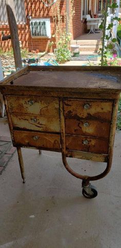 an old wooden table with wheels on the top and bottom is sitting in front of a house