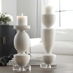 two white candles sitting on top of a table