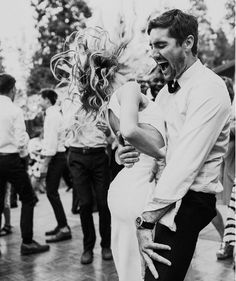 a man and woman dancing on the street with other people in the back ground behind them