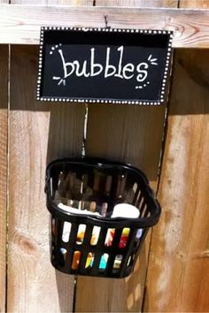 a black basket hanging from the side of a wooden fence with bubbles written on it