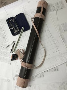 a black and tan bag sitting on top of a table next to some pens and pencils