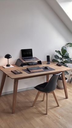 a wooden desk topped with a laptop computer next to a lamp and potted plant