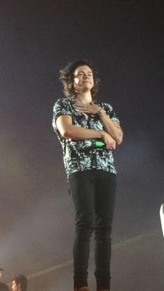 a man standing on top of a stage with his arms crossed and looking up at the sky