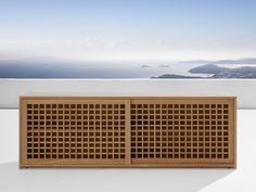 a wooden cabinet sitting on top of a white floor next to an ocean and sky