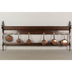 an old wooden rack with pots and pans hanging on it's sides in front of a white wall