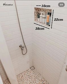 a bathroom with white tile and brown speckles on the floor, including shower head