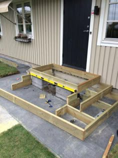 a wooden deck with steps built into the ground in front of a house that is under construction