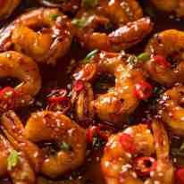 cooked shrimp with sauce and herbs in a pan