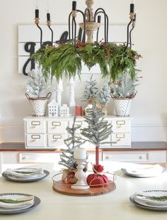 a dining room table decorated for christmas with evergreens, pine cones and other holiday decorations