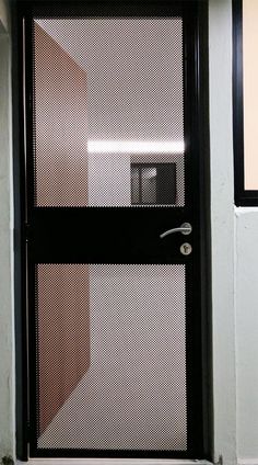 a black door with mesh screen on the side and a white toilet in the corner