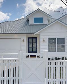 a white house with a blue front door and fenced in area next to it