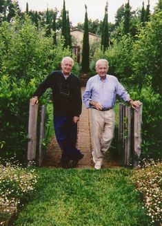 two older men walking down a wooden bridge