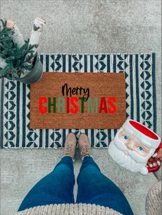 a person standing in front of a door mat with the words merry christmas on it