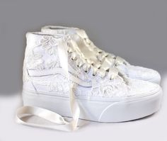 a pair of white shoes with lace on the top and bottom, tied in a white ribbon