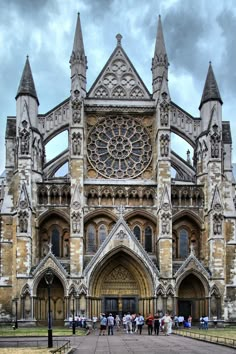 several people are standing in front of an old building with many spires on it