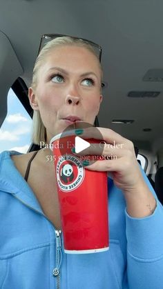 a woman drinking from a red cup while sitting in the back seat of a car