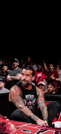 a man with tattoos sitting in front of a crowd