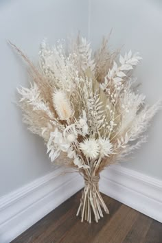 a bouquet of dried flowers sitting on top of a wooden floor next to a wall